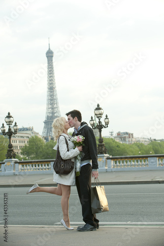 Photo: Caucasian couple kissing on bridge with Eiffel Tower in background Caucasian couple kissing on bridge with Eiffel Tower in background
