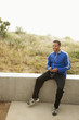 Mixed race man with mp3 player sitting on cement railing