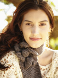 Photo: Close up of gorgeous woman in nature wearing a gray knit scarf smiling at the camera Close up of gorgeous woman in nature wearing a gray knit scarf smiling at the camera