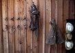 Bridles, saddle, chaps and cowboy hats hanging on wooden wall
