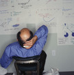 Businessman looking at drawings on office wall