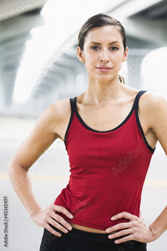 Photo: Hispanic woman in sportswear standing in urban area Hispanic woman in sportswear standing in urban area