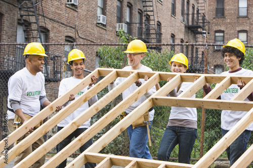 Photo: Volunteers lifting construction frame together Volunteers lifting construction frame together