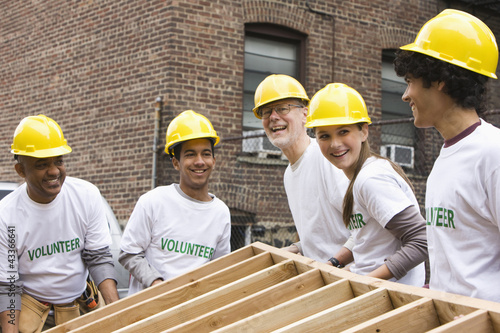 Photo: Volunteers lifting construction frame together Volunteers lifting construction frame together