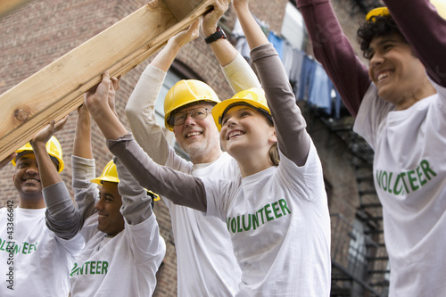 Photo: Volunteers lifting construction frame together Volunteers lifting construction frame together