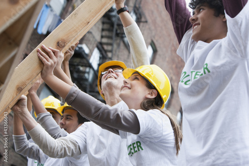Photo: Volunteers lifting construction frame together Volunteers lifting construction frame together