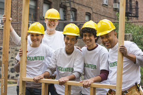 Photo: Volunteers lifting construction frame together Volunteers lifting construction frame together
