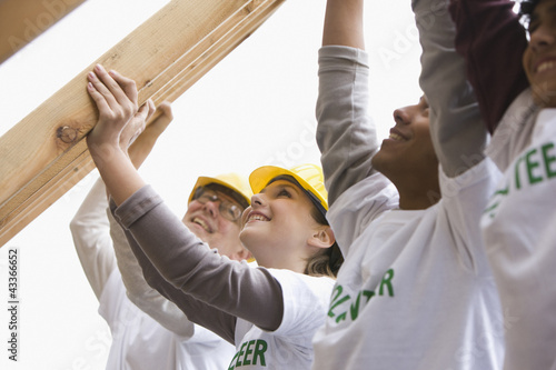 Photo: Volunteers lifting construction frame together Volunteers lifting construction frame together