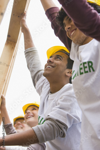 Photo: Volunteers lifting construction frame together Volunteers lifting construction frame together