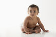 Serious mixed race baby girl sitting on floor