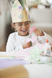 Mixed race girl in crown cutting paper