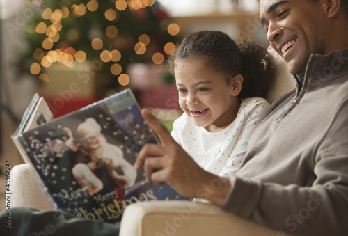 Photo: Father reading Christmas book to daughter Father reading Christmas book to daughter