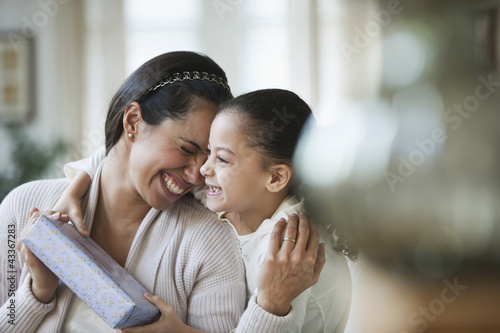 Photo: Hispanic girl giving mother birthday gift Hispanic girl giving mother birthday gift