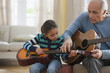 Grandfather teaching granddaughter how to play guitar