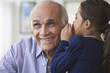 Granddaughter whispering to grandfather