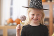 Caucasian girl in witch Halloween costume holding candy apple