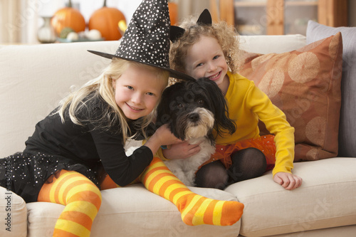 Photo: Caucasian girls in Halloween costumes hugging dog Caucasian girls in Halloween costumes hugging dog