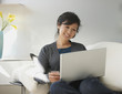 Chinese woman using laptop on sofa