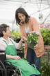Caucasian worker in wheelchair helping customer in nursery