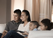 Hispanic family sitting on sofa watching television