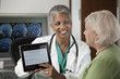 Doctor using digital tablet while talking to patient
