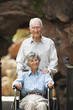 Senior man pushing wife in wheelchair