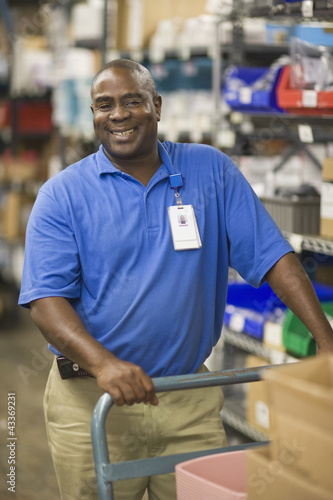 Photo: Man standing in warehouse with inventory and hand cart Man standing in warehouse with inventory and hand cart