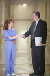 Doctor and businessman shaking hands in hospital corridor
