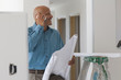 Hispanic architect holding blueprints and talking on cell phone