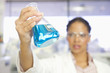 Mixed race scientist lifting beaker in laboratory