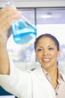 Mixed race scientist lifting beaker in laboratory