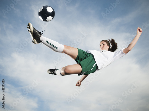 Photo: Caucasian teenager kicking soccer ball in mid-air Caucasian teenager kicking soccer ball in mid-air