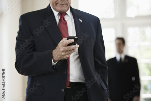 Photo: Caucasian businessman text messaging on cell phone Caucasian businessman text messaging on cell phone