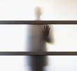 Businessman standing behind glass wall in office