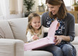 Caucasian mother watching daughter opening gift