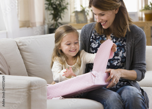 Photo: Caucasian mother watching daughter opening gift Caucasian mother watching daughter opening gift
