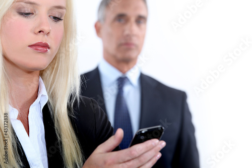 Foto: Woman with mobile and man in the background Woman with mobile and man in the background