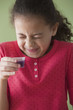 Hispanic girl taking cough syrup