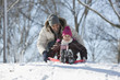Father and daughter sledding on snow covered hill