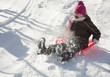 Hispanic girl sledding on snow covered hill