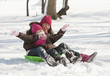 Hispanic girls sledding on snow covered hill