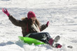 Hispanic girl sledding on snow covered hill