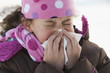 Hispanic girl blowing her nose outdoors in winter