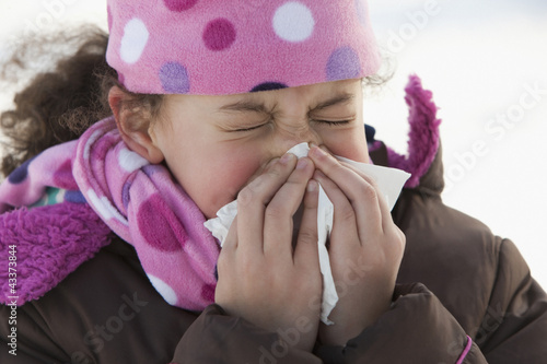 Photo: Hispanic girl blowing her nose outdoors in winter Hispanic girl blowing her nose outdoors in winter