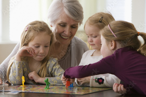 Photo: Caucasian grandmother and granddaughters playing game together Caucasian grandmother and granddaughters playing game together