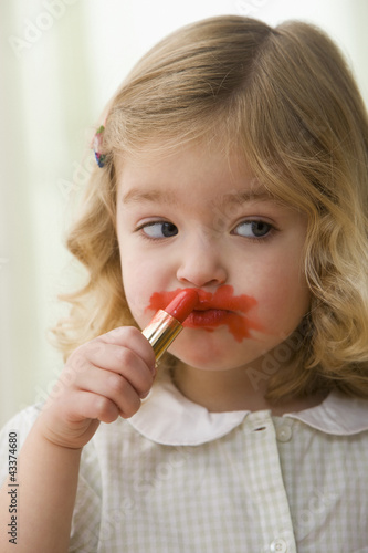 Photo: Caucasian girl putting on lipstick Caucasian girl putting on lipstick