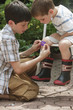 Boy putting bandage on brother's knee