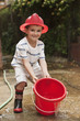 Caucasian boy playing with bucket wearing fireman's hat