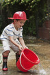 Caucasian boy playing with bucket wearing fireman's hat