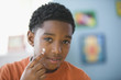 Mixed race boy applying acne lotion
